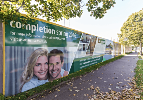 Ashtons hoarding Shiny green hoarding with graphics and information printed on it.